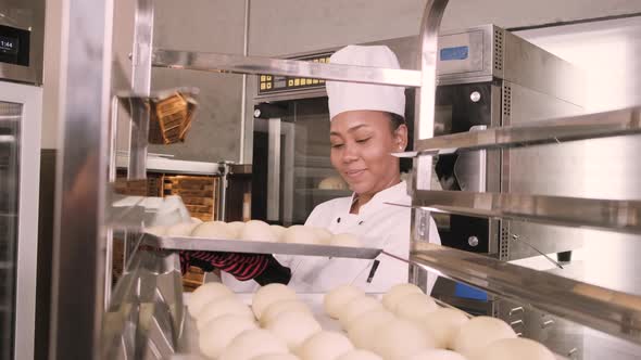 Female chef in uniform prepare to bake bread and pastry in stainless kitchen.