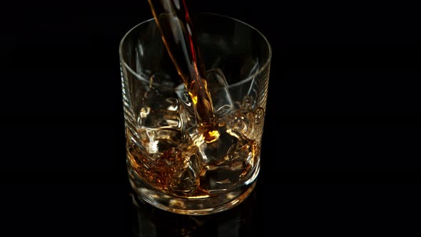 Super Slow Motion Shot of Pouring Whiskey Into Glass with Ice Cubes at 1000Fps with Camera Movement. alt