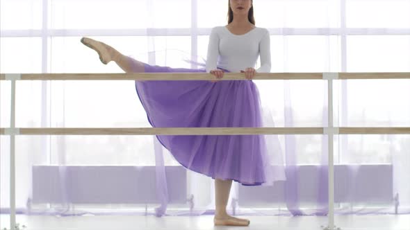 Professional Ballerina is Puts Her Leg on the Barre Stand