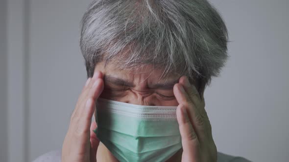 Sick Asian man wearing a medical face mask and Take a hand to hold the headache alt