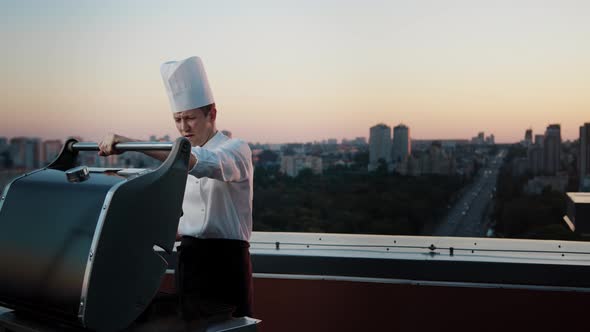 A professional Chef prepares a barbecue on the rooftop of a skyscraper. An expensive restaurant alt