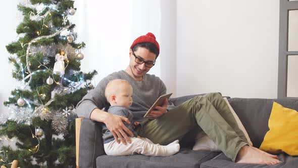Young Father with Little Son Playing on Tablet Computer Christmas.