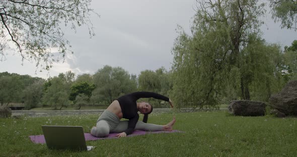 Fit Woman Watching Online Fitness Videos on Laptop and Doing Sports in the Park alt