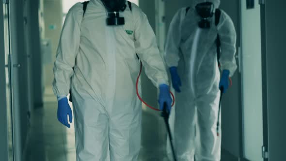 People Sanitize Hallway with Sprayers During Pandemic. alt
