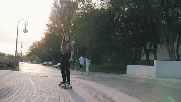Happy girl is skateboarding at summer holidays and weekend, young woman is riding on skateboard, spo