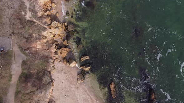 Aerial view drone flies over the ocean. The waves beat against the stones.