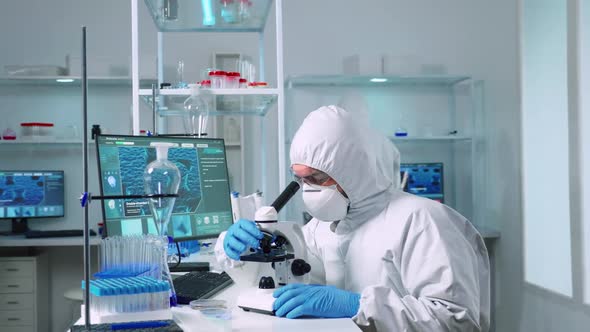 Scientist in Ppe Suit Working in Laboratory Using Modern Microscope alt
