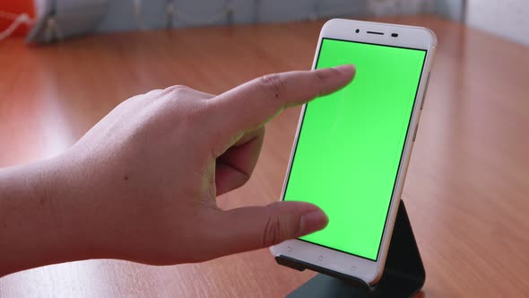 Slide motion of the male hand is sliding and touching the phone with the green screen is placed on t alt