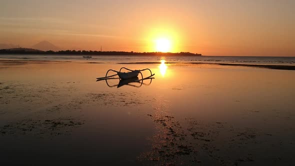 Aerial video of a boat silhouetted in the sunset on a beach in Bali, Indonesia (1)