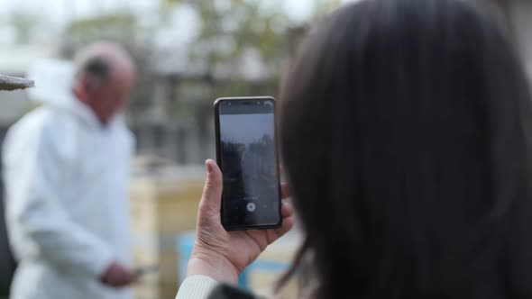 Elderly Influencer, Man in Protective Suit Writes Video for Blog About an Apiary Background of alt