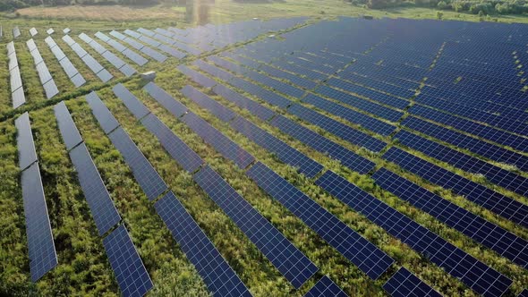 Top view of a massive photovoltaic power station located in a field at sunset. Solar energy power alt