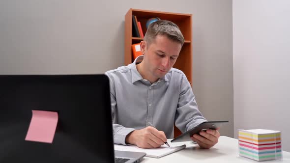 Young Male Office Worker Holding a Tablet in His Hands in Remote Work alt