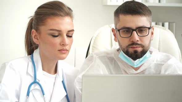 Female and Male Doctors Discuss Patients Diagnosis at Laptop in Clinic alt