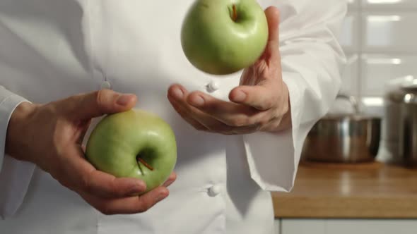 Chief-Cooker Juggles A Green Apples In A Kitchen