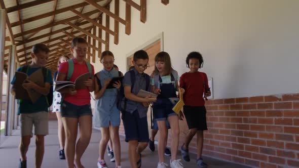 Group of kids with books walking in the school corridor alt
