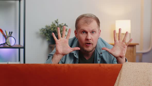 Man Playing Hide and Seek Peekaboo Game Hiding Behind Sofa Looking at Camera Positive Smiling alt