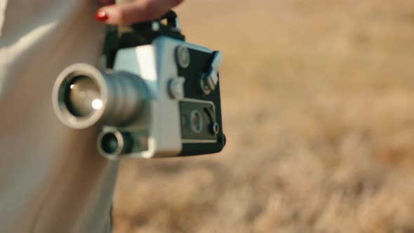 Vintage 8Mm Cinema Camera in the Hand of a Girl Walking in the Countryside alt