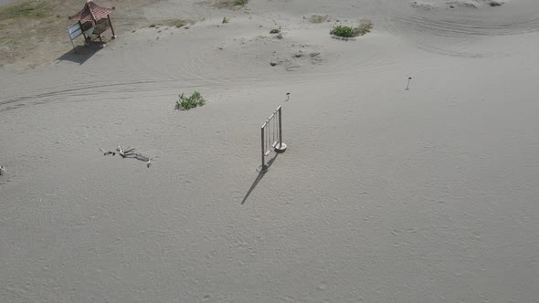 The old rope wooden swing on the desert or sandy beach with mountain background alt