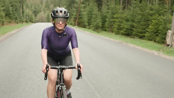 Woman on bike. Female rides bicycle on mountain road. Cyclist cycling on road bike. alt