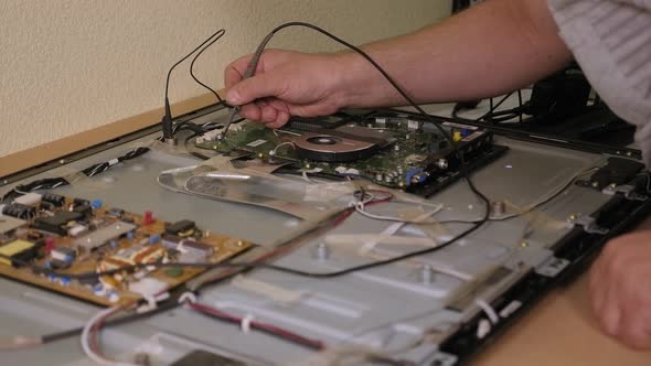 A Technician Checks the Voltage in the Motherboard While Repairing the TV alt