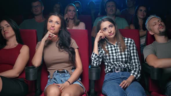 Two Upset Woman Friends Watching Bad Film with Unpleasant Negative Emotion Bored at Cinema alt
