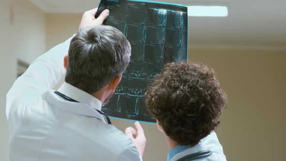 Male and female doctors examining X-ray pictures of spine