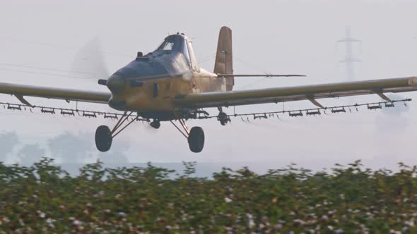 Crop duster spraying chemicals over a cotton field - slow motion alt