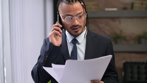 A stylish black company executive is discussing something over the phone alt