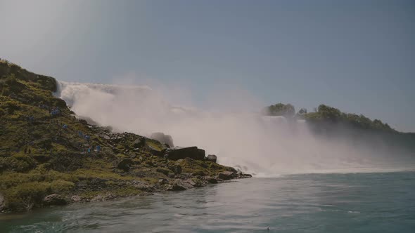 Cinematic Shot of Tourists in Raincoats Watching Epic Wall of Water at Beautiful Famous Niagara alt