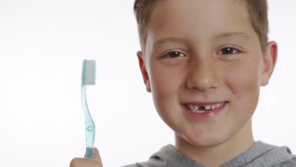 Closeup Portrait Happy Smiling Boy Holding a Toothbrush. Cheerful Boy Without a Front Tooth alt
