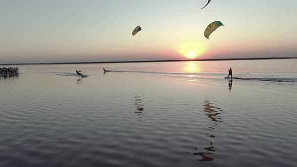 Aerial Footage of Kite Surfers Gliding on a Pink Lake During Sunset,  alt