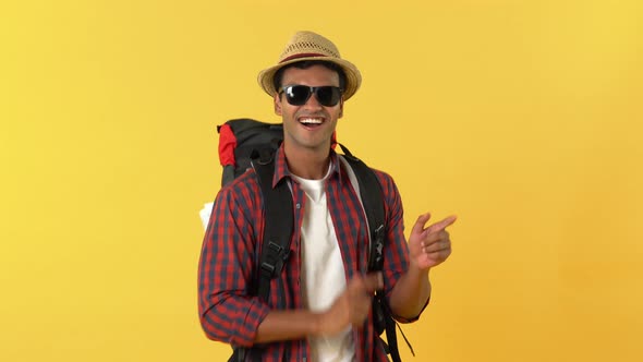 Portrait of smiling indian tourist man with backpack dancing