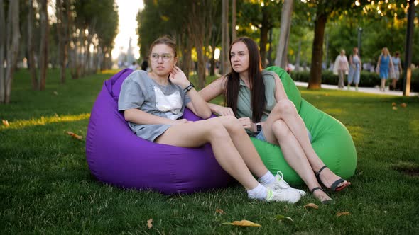 A Woman and Her Teenage Daughter are Sitting Together on Large Colored Pillows on the Lawn in the