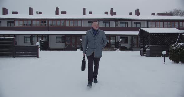 Business Man Leaves Home With A Briefcase And Goes To Work In Winter