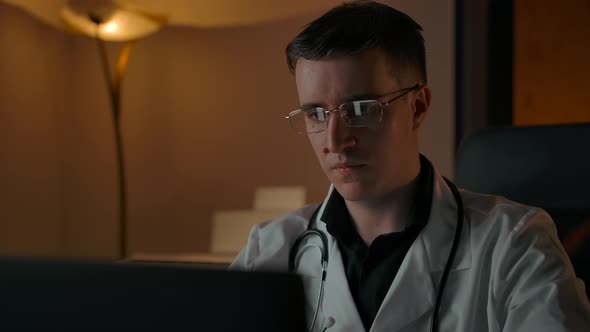 Portrait of Home Working Doctor Behind Laptop Looking at Camera alt
