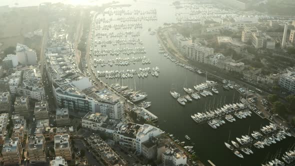 Sailboat Port with White Yachts and Boats in Sunlight Morning on Marina Malta, Aerial Tilt Down  alt