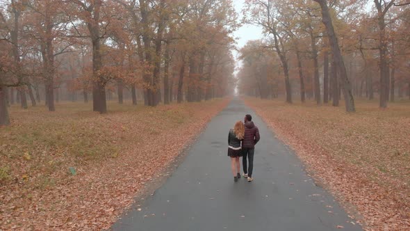 Interracial Love Concept. Beautiful Young Interracial Couple Walking on Road in the Foggy Autumn alt