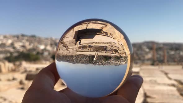 Crystal Ball Reflection Against Ancient Ruins of Roman City, Columns, Hand Holding