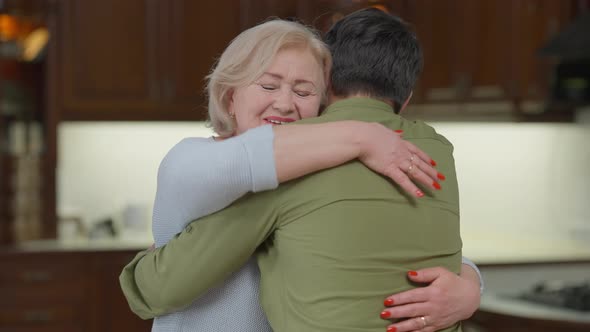 Portrait of Excited Senior Woman Hugging Adult Man Looking at Camera with Happy Facial Expression alt