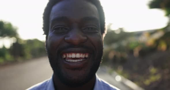 Young african man smiling on camera in the city with sunset in the background alt