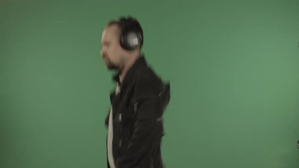 Young Handsome Man with Headphones Dancing on the Background of a Green Screen