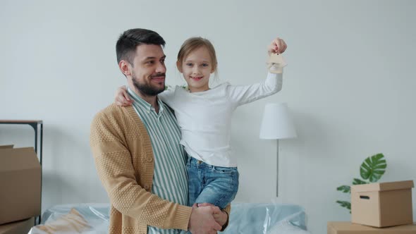 Portrait of Young Dad and Cute Daughter Holding Apartment Keys Smiling Looking at Camera alt