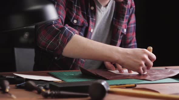 Man Tailor Cutting Artificial Leather with Ruler Closeup alt