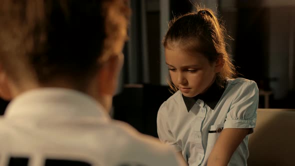 Young pretty girl of school age plays a concentrated game of chess with a classmate