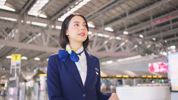 Beautiful Caucasian flight attendant staff smiling and walking with confidence in airport terminal. alt