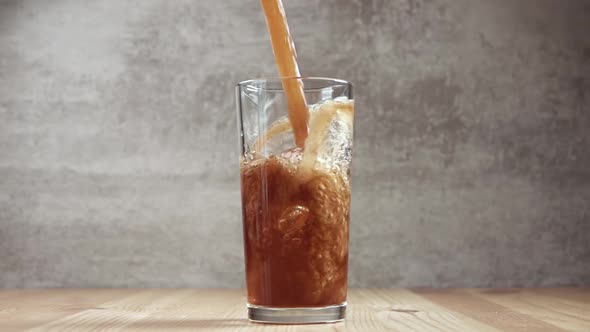 Carbonated Drink is Poured Into a Glass With Ice Cubes