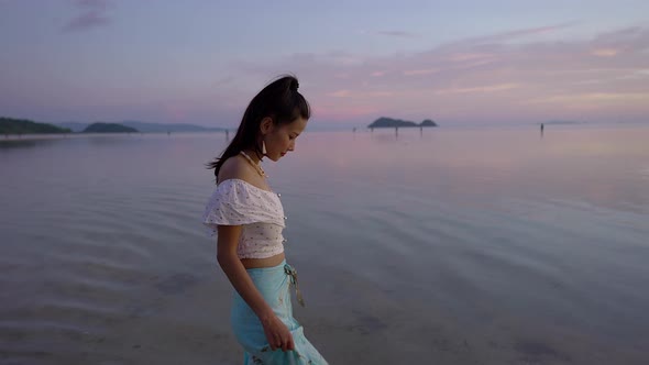 Cute Asian Woman Walking Alone in the Sea at Beautiful Sunset Thailand