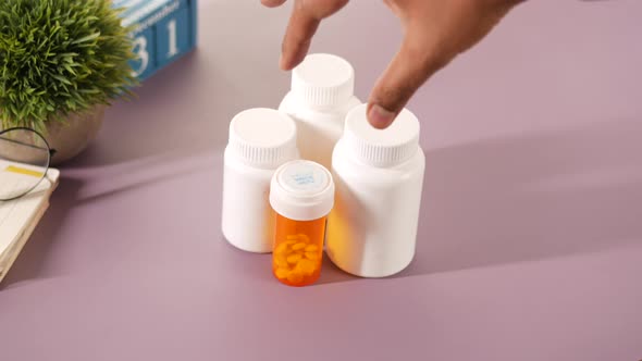 Hand Pick a Medical Pill Container on Table alt