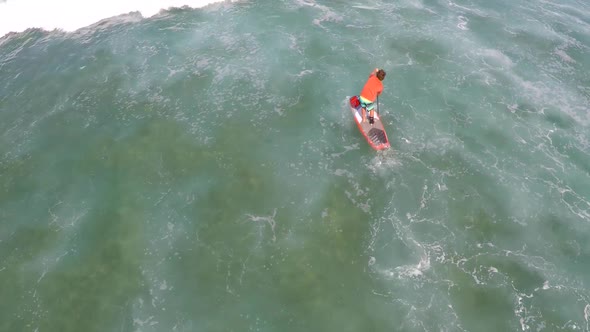 Aerial view of a man sup stand-up paddleboard surfing in Hawaii alt