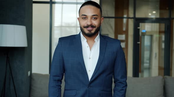 Slow Motion of Handsome Middle Eastern Man in Suit Standing Alone in Hotel Lobby Smiling alt